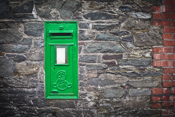 Shot of a green letter box on a stone wall